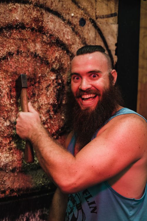 Free Muscular man with a beard excitedly holding an axe after a throw at a target. Stock Photo