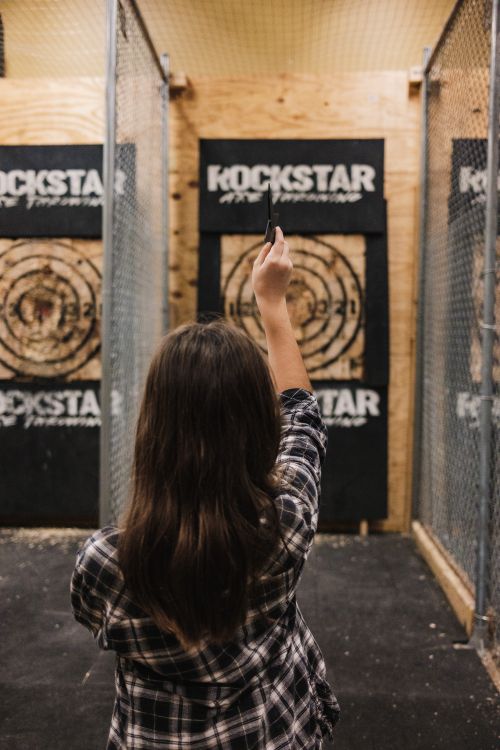 Free Young woman throws an axe at a target in an indoor range, showcasing skill and focus. Stock Photo