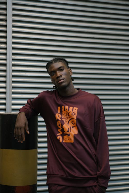 A Man in a Maroon Long Sleeves Leaning on a Barrier