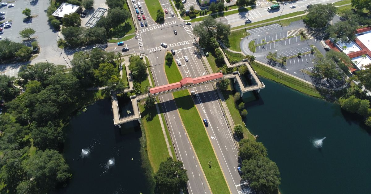 A stunning aerial view of a busy intersection and footbridge surrounded by water in Lake Mary, Florida.