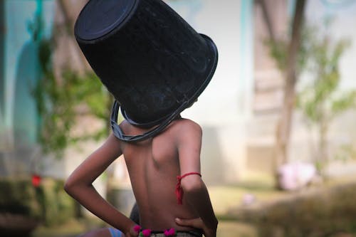 Photograph of a Bucket on a Boy's Head