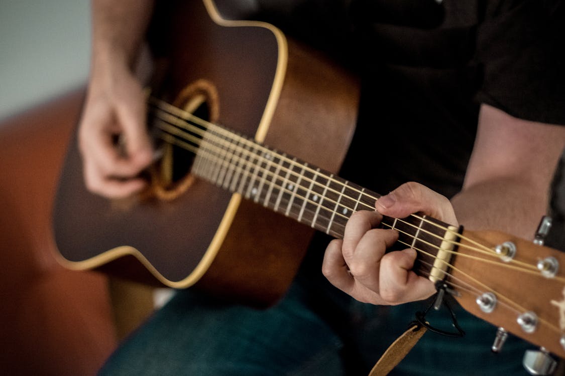 Free Person Playing Brown Guitar Stock Photo