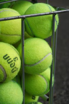 Close-up of vibrant tennis balls stored in a metal hopper, showcasing texture.