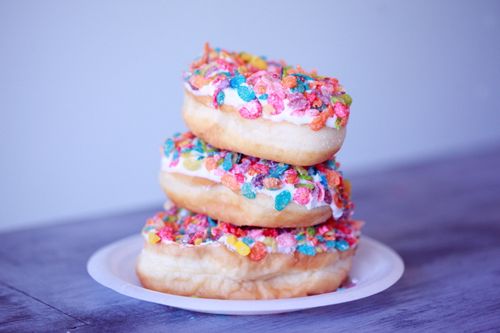 Free A stack of doughnuts covered in colorful fruity pebbles on a plate. Stock Photo