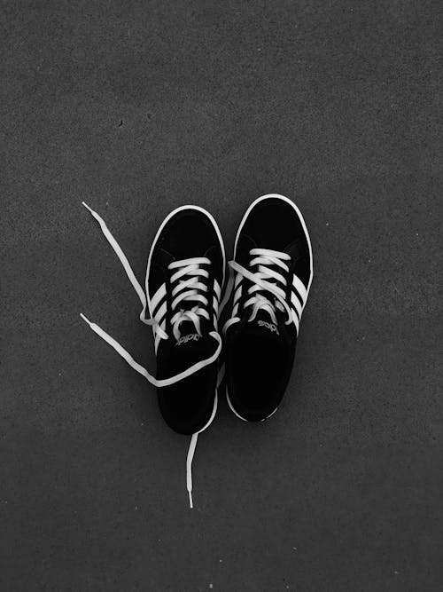 一對灰色地板上的黑白阿迪達斯運動鞋