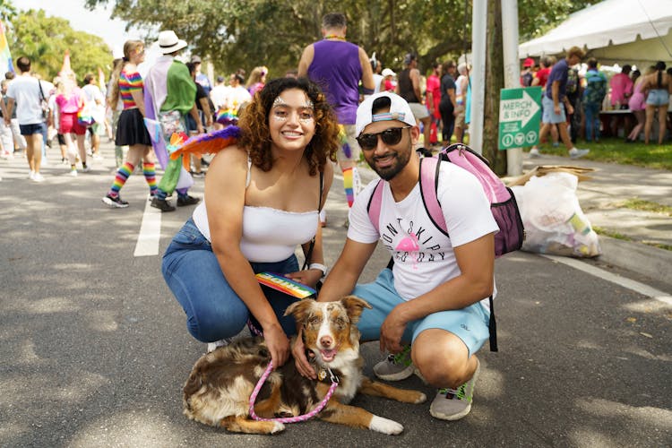 A Man And Woman Holding A Dog 