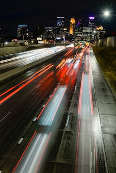 Dynamic long exposure photo of city traffic with illuminated skyline at night.