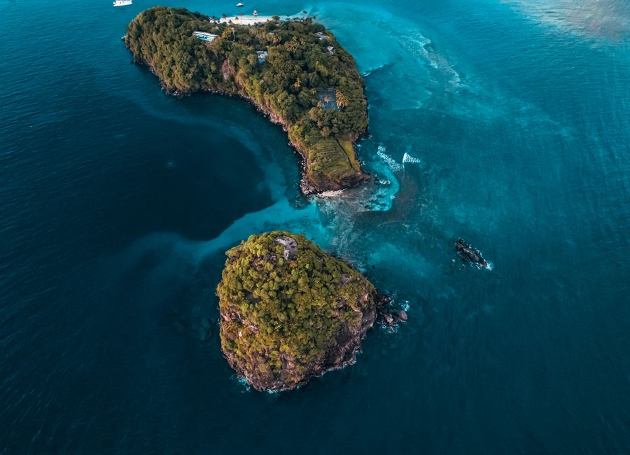 Stunning aerial shot of a remote island surrounded by vibrant blue ocean waters.