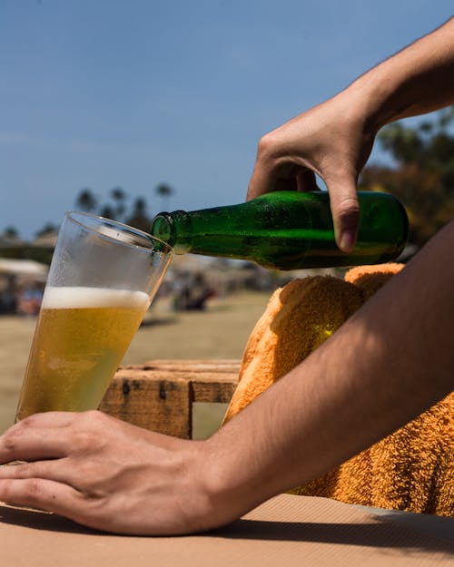 Ücretsiz Şeffaf Cam üzerine Bira Dökülen Yeşil şişe Tutan Kişi Stok Fotoğraflar