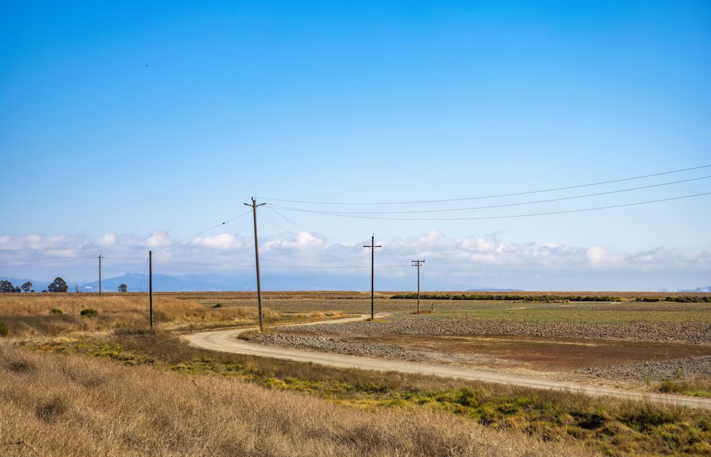 Open countryside with power lines and a clear blue sky, ideal for depicting rural tranquility.