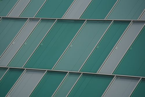 Free Close-up of a modern glass facade with teal panels, highlighting contemporary architecture. Stock Photo
