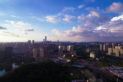 A stunning aerial view of a modern cityscape under a dramatic sky at dusk, highlighting tall buildings and vibrant clouds.