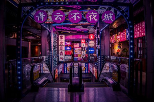 Free Vibrantly lit entrance of a shopping mall with neon signs in Chinese characters and escalators. Stock Photo