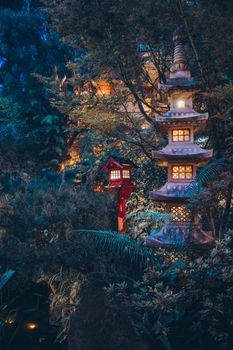 A beautifully illuminated pagoda in a dense forest creating a tranquil and exotic ambiance.