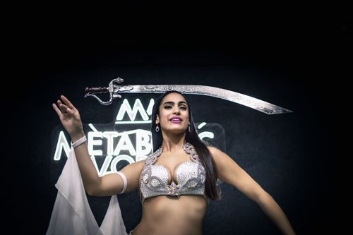 Free Belly dancer gracefully performing with a sword, displaying cultural dance art. Stock Photo