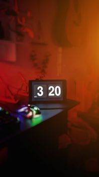 Vertical shot of an illuminated digital clock indoors with a colorful ambient glow.