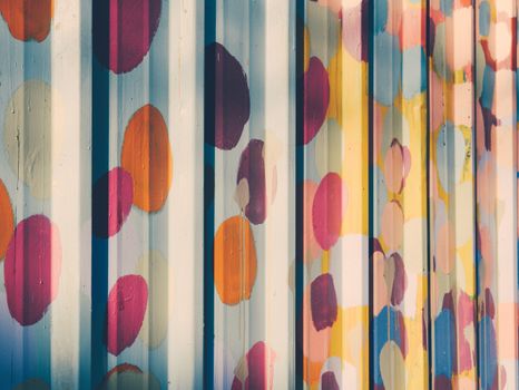 Artistic metal wall displaying a colorful painted pattern with a corrugated texture.