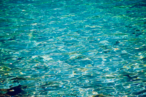 Free A soothing image of clear blue water with soft ripples and reflections. Stock Photo