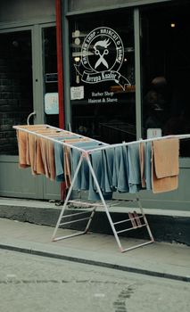 Barber shop exterior with towels drying on a rack outside the storefront.