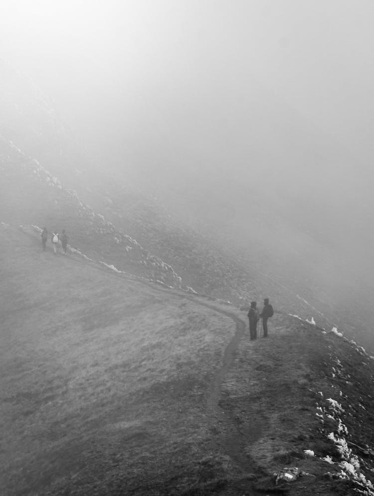 People Hiking The Mountain On A Foggy Day