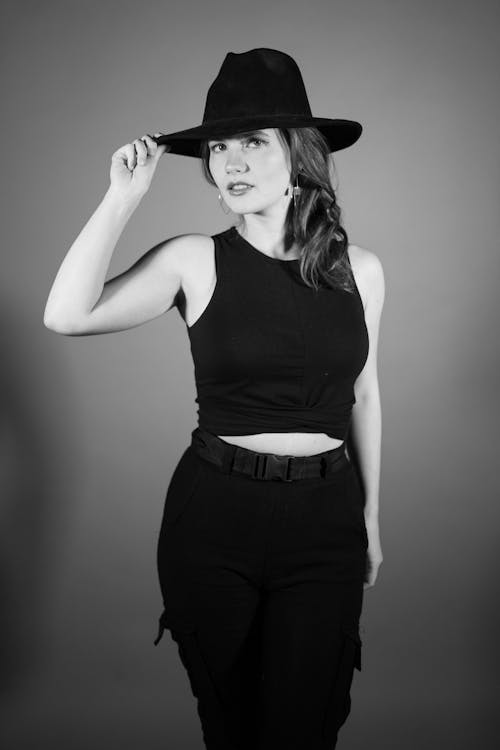 A Grayscale Photo of a Woman in Black Tank Top Wearing a Hat