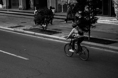 Grayscale Photo of Man Riding Bicycle on Road