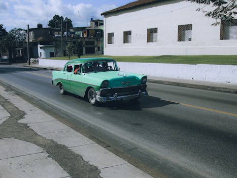 Vintage green Chevrolet Bel Air cruising through a sunny urban landscape.