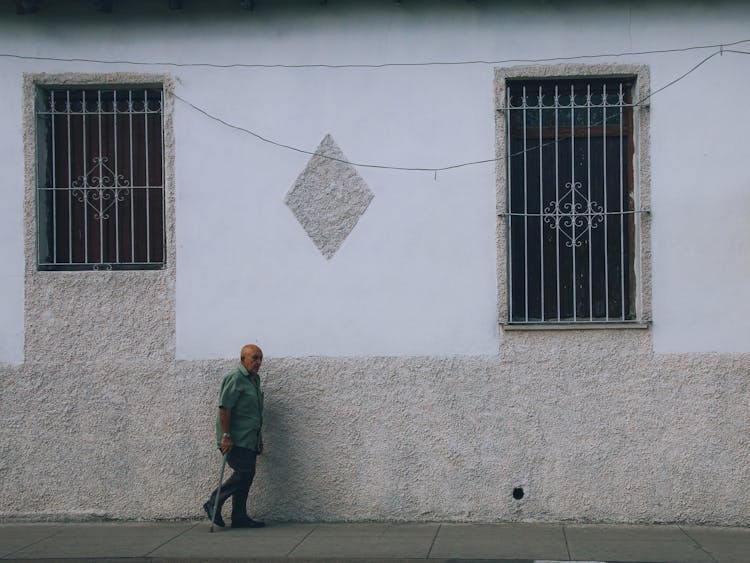 A Man Walking On A Sidewalk