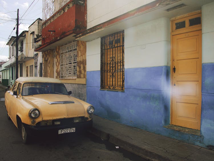 Yellow Car Parked Beside A House 