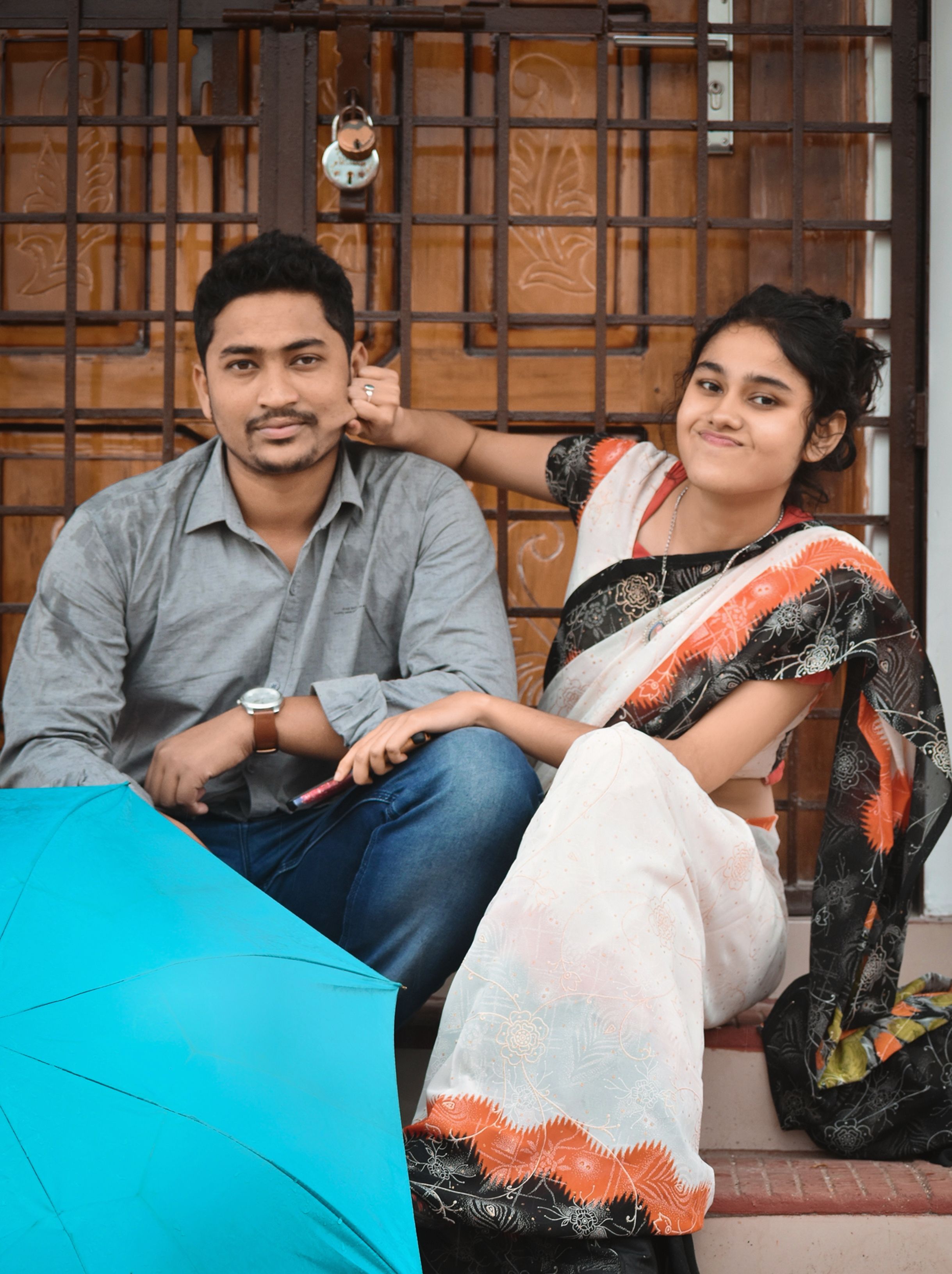 Indian couple sharing a joyful moment under a vibrant umbrella outdoors in Barpeta, Assam.