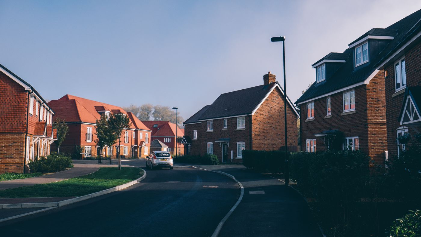 A quiet English suburban street lined with red-brick houses at first light
