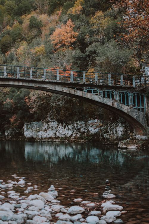 Free Discover the peaceful beauty of a rustic bridge surrounded by vibrant autumn foliage in Greece. Stock Photo