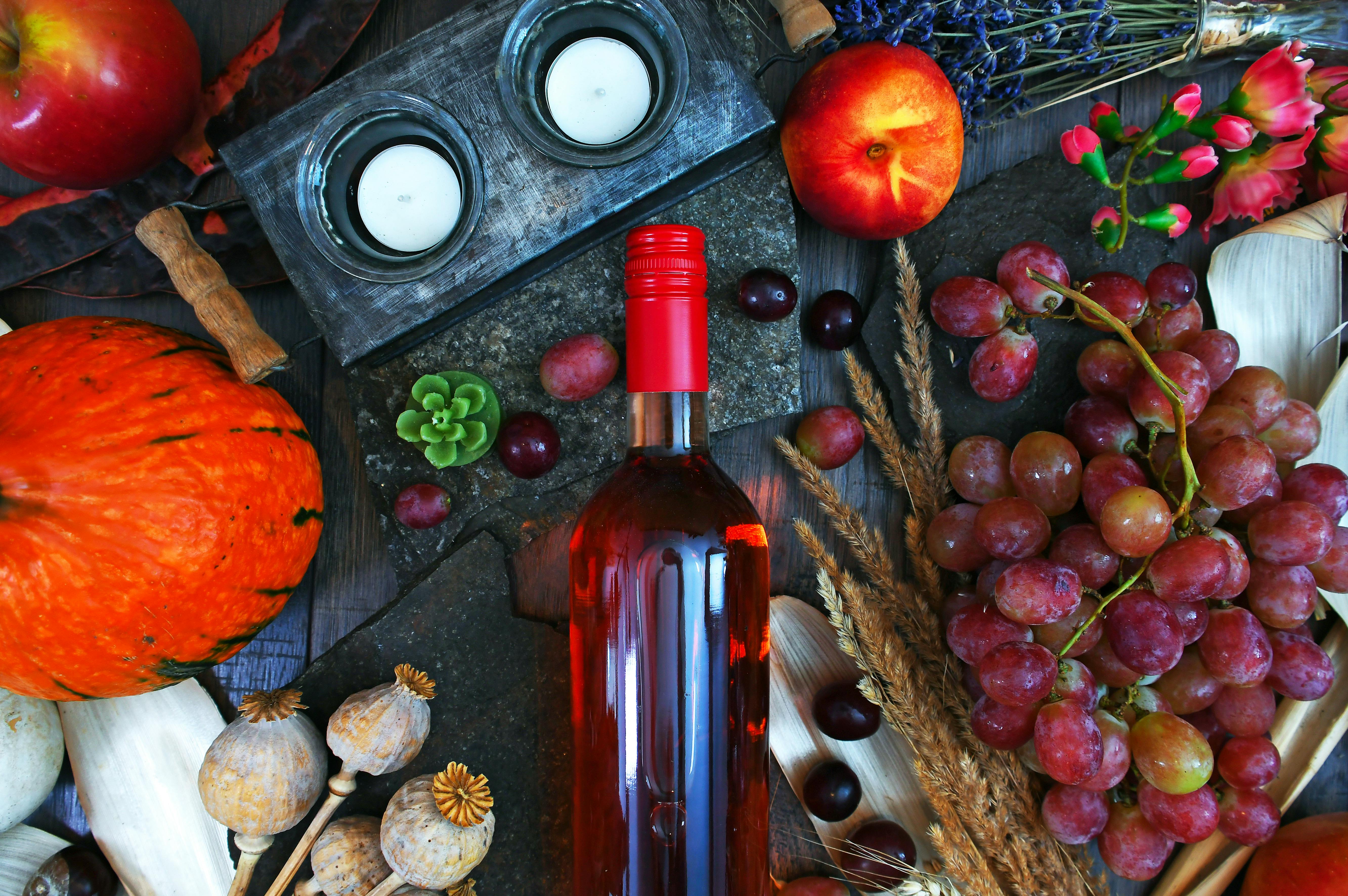 clear glass wine bottle surrounded by fruits top view photography