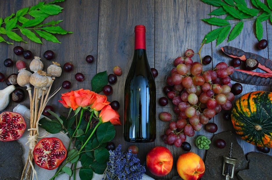 Botella de vino junto a uvas, rosas y varias frutas sobre la superficie de madera marrón