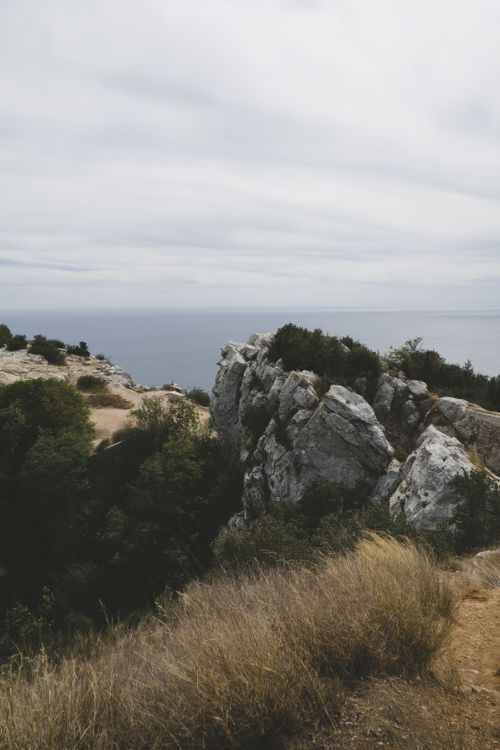 Free Explore a serene ocean view from a natural rock formation with lush greenery and rugged cliffs. Stock Photo