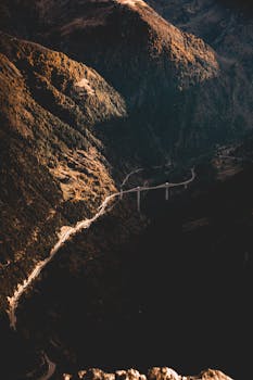 Drone shot of a bridge crossing a scenic mountain gorge, ideal for travel and nature themes.