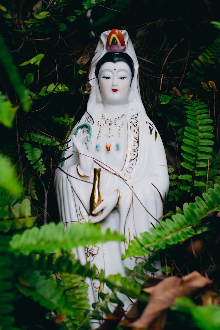 White Guanyin Statue Near Fern Plants