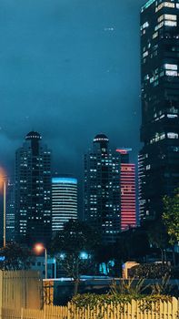 A vibrant urban night scene showcasing illuminated skyscrapers against a dark sky.