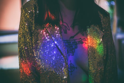 Close-up of a woman's tattoo and shimmering jacket with rainbow light reflections.