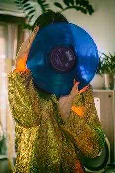 一位穿着金色亮片夹克的女人，在室内手持蓝色乙烯基唱片，复古氛围十足