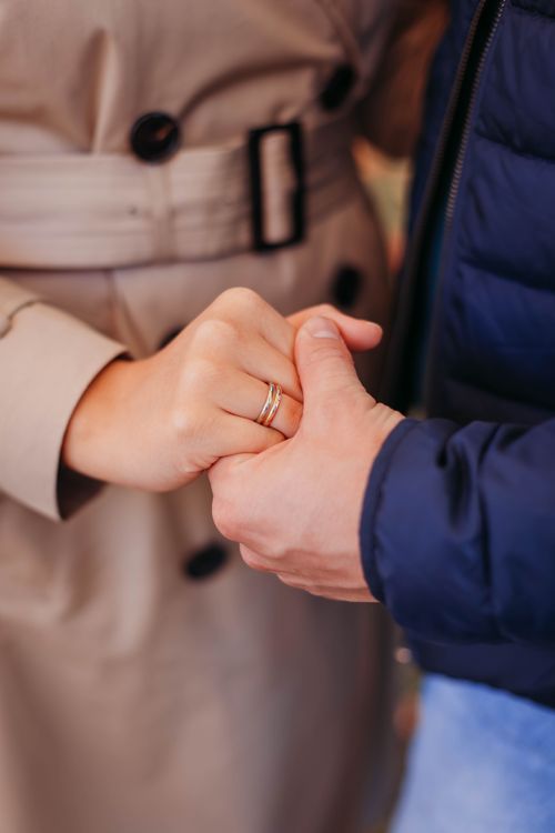 Free Close-up of a couple's hands with wedding rings, expressing love and affection. Stock Photo
