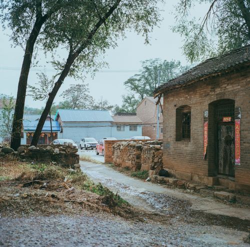 Free A tranquil village street with traditional buildings under a rainy sky. Perfect for rural scenes. Stock Photo