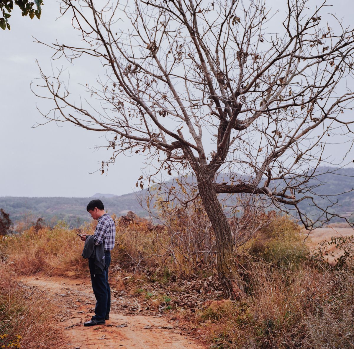 Final whistle territory: checking the phone alone on a dirt path with open hill country behind, the exact ground where an eSIM either holds up or doesn't.