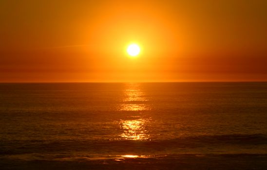 A breathtaking sunset over the calm ocean with vibrant orange hues.