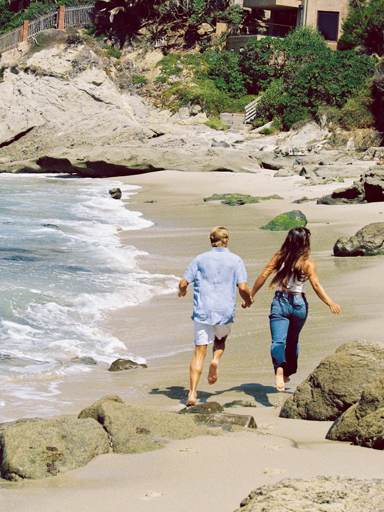 A Couple Running On The Beach