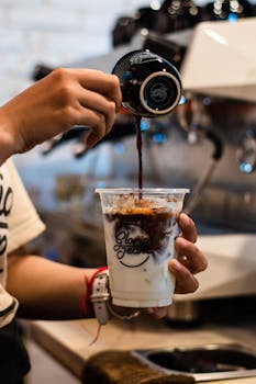 A barista pouring coffee into an iced latte cup at a cafe in Phnom Penh, Cambodia.