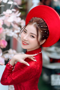 Stylish portrait of a smiling woman wearing traditional red Áo Dài and hat.