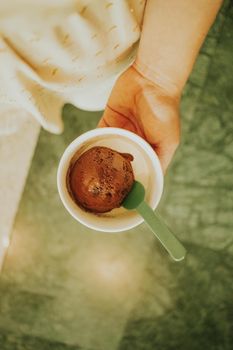 Delicious chocolate ice cream in a paper cup held by a person's hand. Perfect for dessert themes.