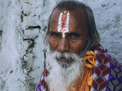 Free Portrait of an elderly man with traditional face markings and colorful attire. Stock Photo