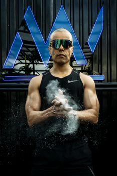 Fit man clapping chalk dust in a black tank top, showcasing fitness style